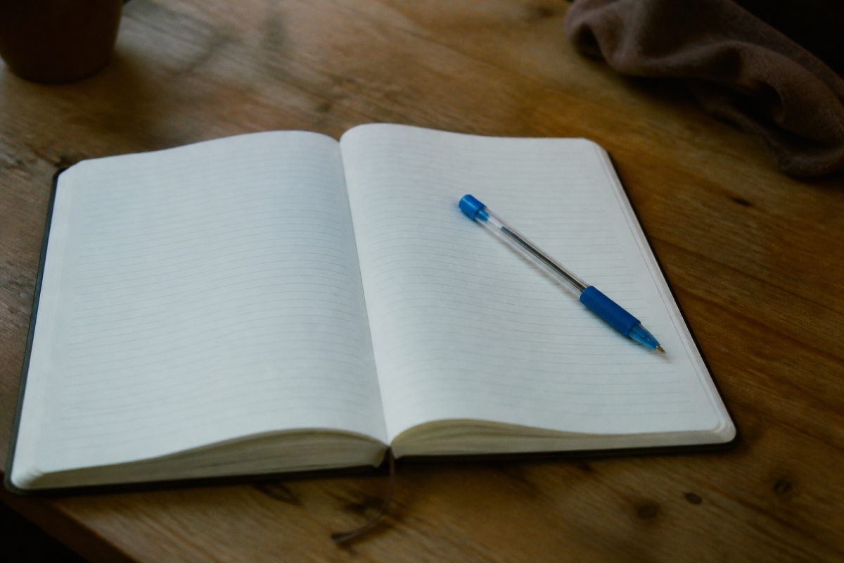 Journal papier ouvert sur bureau avec stylo bleu