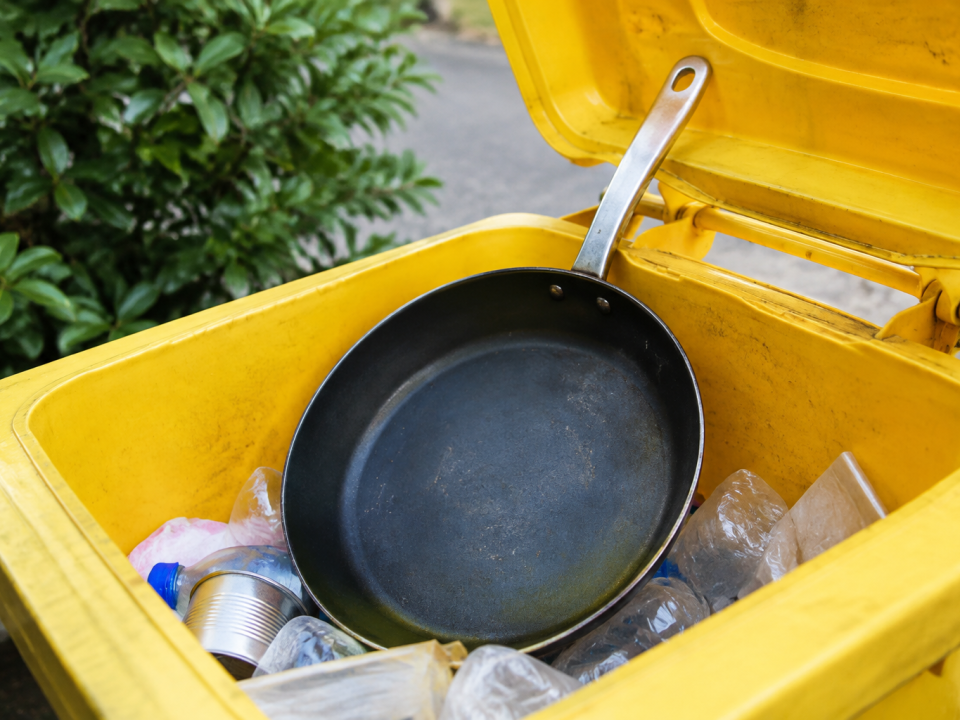 Poele metallique deposee dans bac recyclage jaune